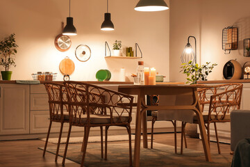 Interior of modern kitchen with glowing lamps, white counters, chairs and dining table at evening