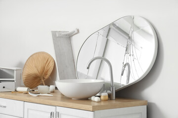 Broken mirror with sink on counter in messy bathroom