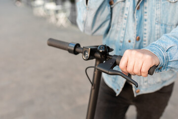 Close-up of male hands holding the steering wheel of an electric scooter.