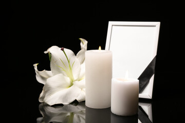 Blank funeral photo frame, candles and lily on black background