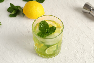 Glass of tasty lemonade with mint and lime slices on white background