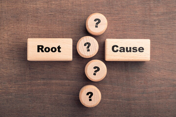Wooden blocks with the words root and cause surrounded by question mark icons arranged like a root...