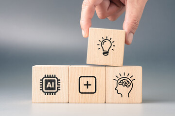 Wooden blocks with icons of AI, brain, and light bulb representing collaboration between artificial...