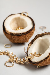 Fresh coconut with beautiful rings and necklace on grey background