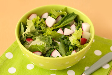 Bowl of tasty salad with radish on color table