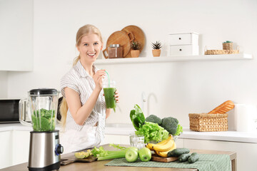 Happy young woman with blender, tasty smoothie and ingredients in kitchen