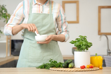 Woman with basil plant and vegetables in kitchen
