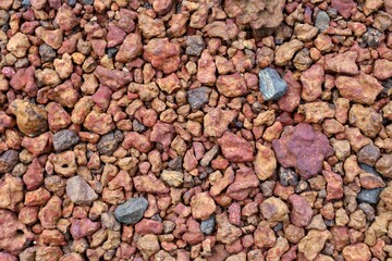 A rough-textured red volcanic rock, formed from cooled lava, showcasing natural pores and vibrant earthy tones, symbolizing the raw power and beauty of volcanic activity. background of colorful stones
