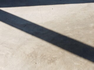 Textured concrete floor with a strong diagonal shadow. A versatile background showcasing light and...