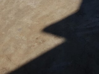 Abstract concrete floor with strong geometric shadows and light, showing texture and cracks....