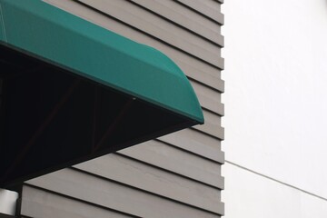 Green awning on modern building facade with horizontal siding and negative space, suitable for...