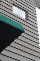 Architectural detail of a modern building facade with a green awning and horizontal siding,...