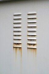 Close-up of light gray industrial panel with two vertical rows of horizontal vents, showing...