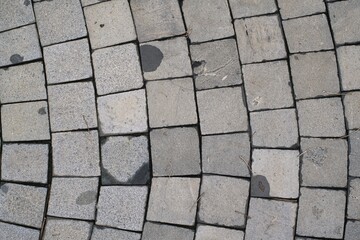 Textured background of old grey paving stones with scattered debris and subtle water stains, ideal for copy space.