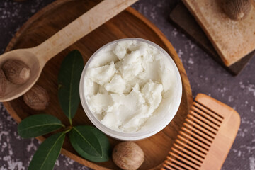 Composition with jar of shea butter, nuts, hair comb and soap on grunge color background, closeup