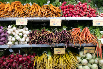 Vibrant display of organic carrots and radishes arranged on supermarket shelves. Bright orange carrots and crisp red radishes with leafy green tops create a colorful, fresh, and appetizing presentatio
