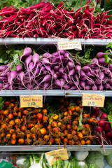 Vibrant display of organic carrots and radishes arranged on supermarket shelves. Bright orange carrots and crisp red radishes with leafy green tops create a colorful, fresh, and appetizing presentatio