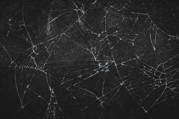 Close-up texture of broken glass with abstract crack patterns, creating a dramatic and artistic look.