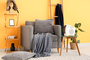 Interior of stylish living room with modern electric fan heater and grey armchair