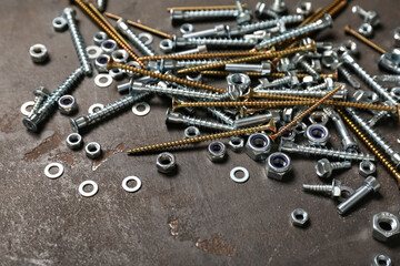 Different screws and chrome nuts on grey grunge background