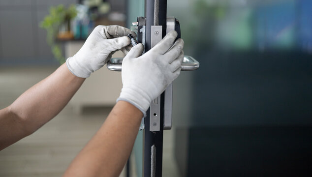 Professional locksmith repairing home entrance access door lock
