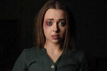 Bruised young woman on dark background, closeup. Domestic violence concept