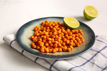 Plate with tasty fried chickpeas and lime on white background