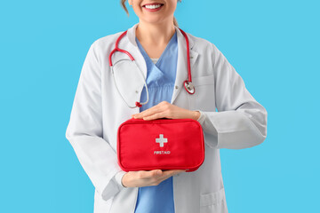 Female doctor with first aid kit on blue background, closeup