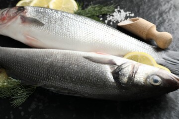 Fresh raw seabass with spices on black table, closeup. Fish and seafood delicacies