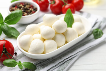 Tasty mozzarella cheese, tomatoes, basil and spices on white wooden table, closeup