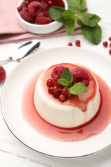 Delicious panna cotta with berries, sauce and mint on white wooden table, closeup