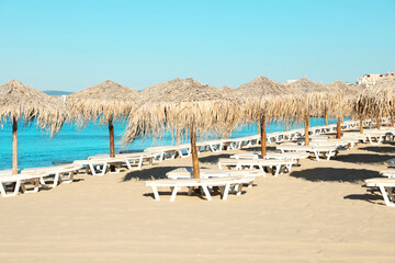 Straw umbrellas and sunbeds on sandy beach