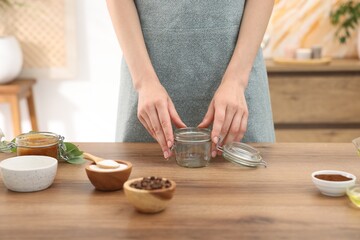 Woman making natural body scrub at wooden table, closeup