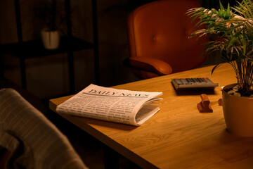 Newspaper on desk in dark office, closeup