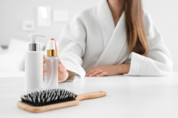 Beautiful young woman with cosmetic products and brush on table in bedroom at home, closeup