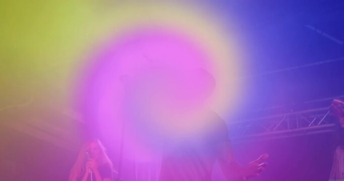 Lead singer raising arm on stage, initiating swirling rainbow spiral overlay energizing performance