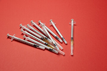 A collection of medical syringes, some filled with liquid, arranged in a scattered formation on a...