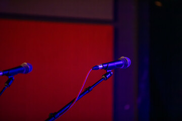 A microphone on a stand on a lit stage before a musical show.
