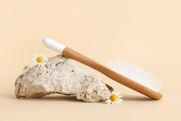 Composition with hair brush, stone and chamomile flowers on color background