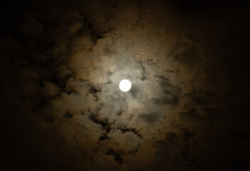 Timelapse of the full moon moving across a cloudy midnight sky. Mysterious space view with blue fog and moonlight shining through dark clouds.