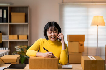 woman in a yellow shirt is talking on the phone while writing in a box