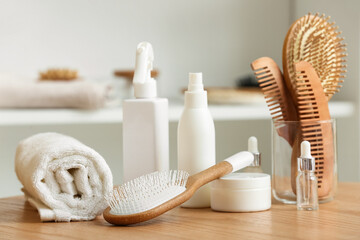 Set of cosmetic products, clean towel, hair brushes and combs on wooden table in room