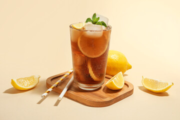 Glass of Long Island iced tea cocktail with mint and lemons on beige background
