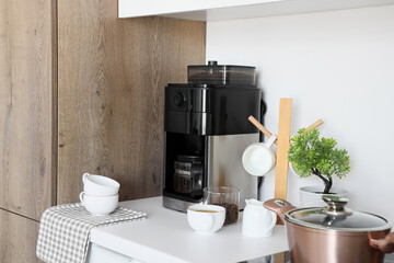 Modern coffee machine, cups and beans on counter in kitchen