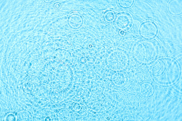 Texture of water with splashes on blue background, top view