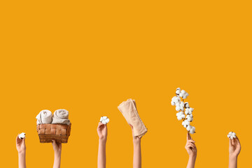 Female hands with cotton flowers and towels on yellow background