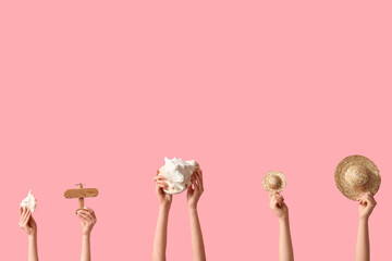 Female hands with seashells, wooden airplane and hats on pink background. Tourism concept