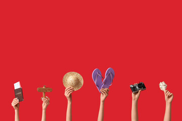 Female hands with beach accessories on red background. Tourism concept