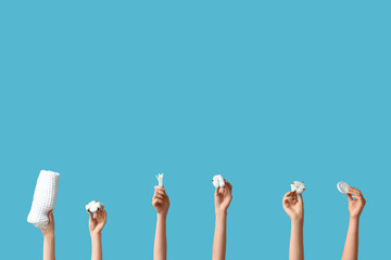 Female hands with cotton flowers, buds, pads and towel on blue background