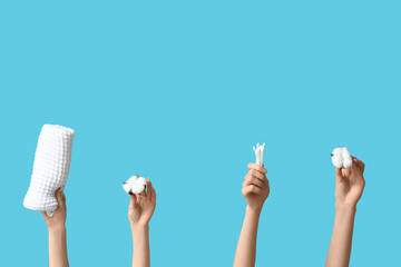Female hands with cotton flowers, buds and towel on blue background